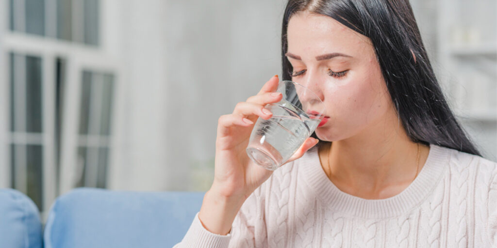 A young woman drinking a glass of water.